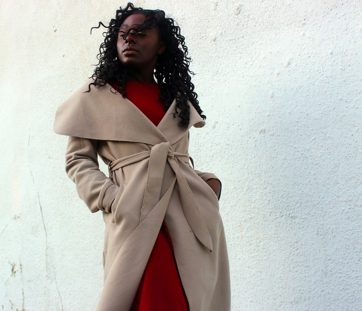 Person in a cream wrap coat with hands in the pockets